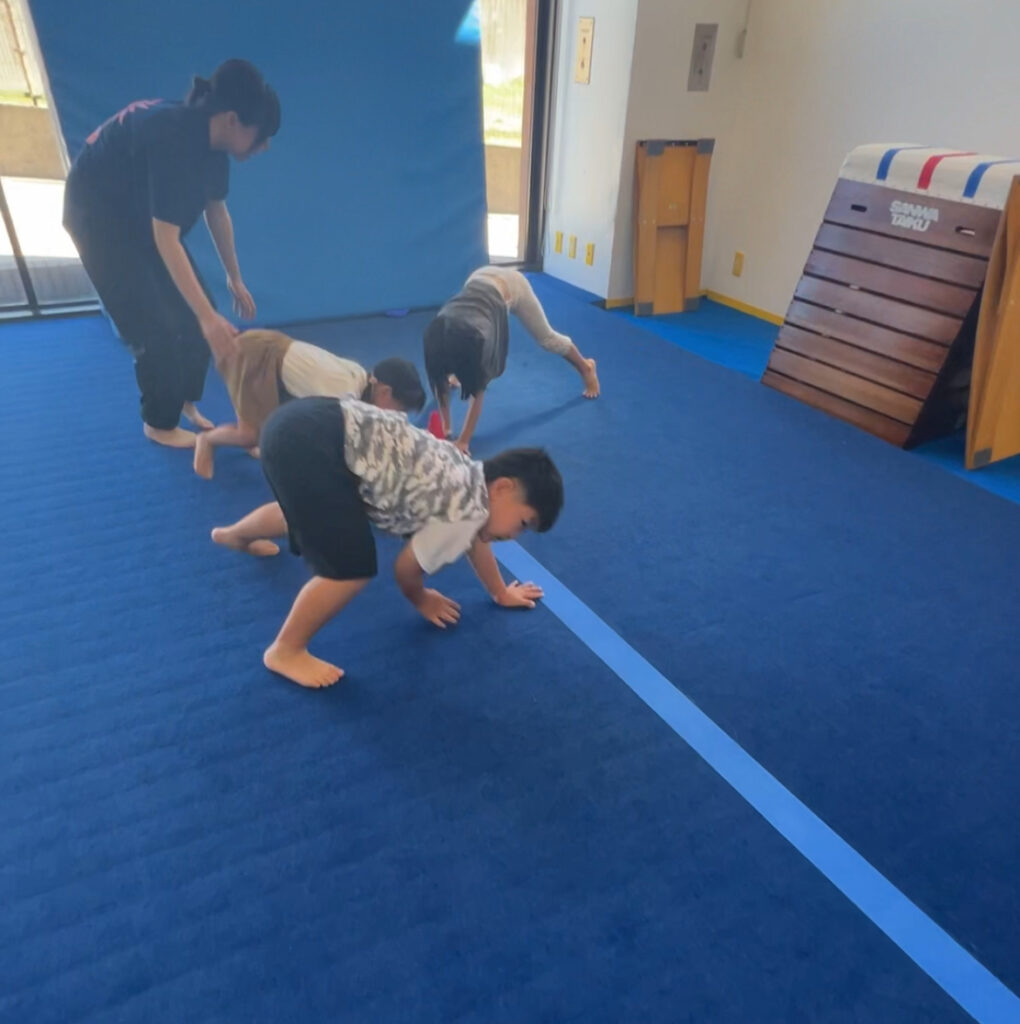 SBCスポーツ教室の体操体幹クラスでコーチの指導を受けながら四つ這い運動に取り組む子どもたち